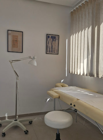 AcuTherapy Center treatment area — serene clinic space with warm neutral tones, professional acupuncture setup and calming atmosphere